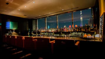 Un bar con vista a una torre, con taburetes y botellas.