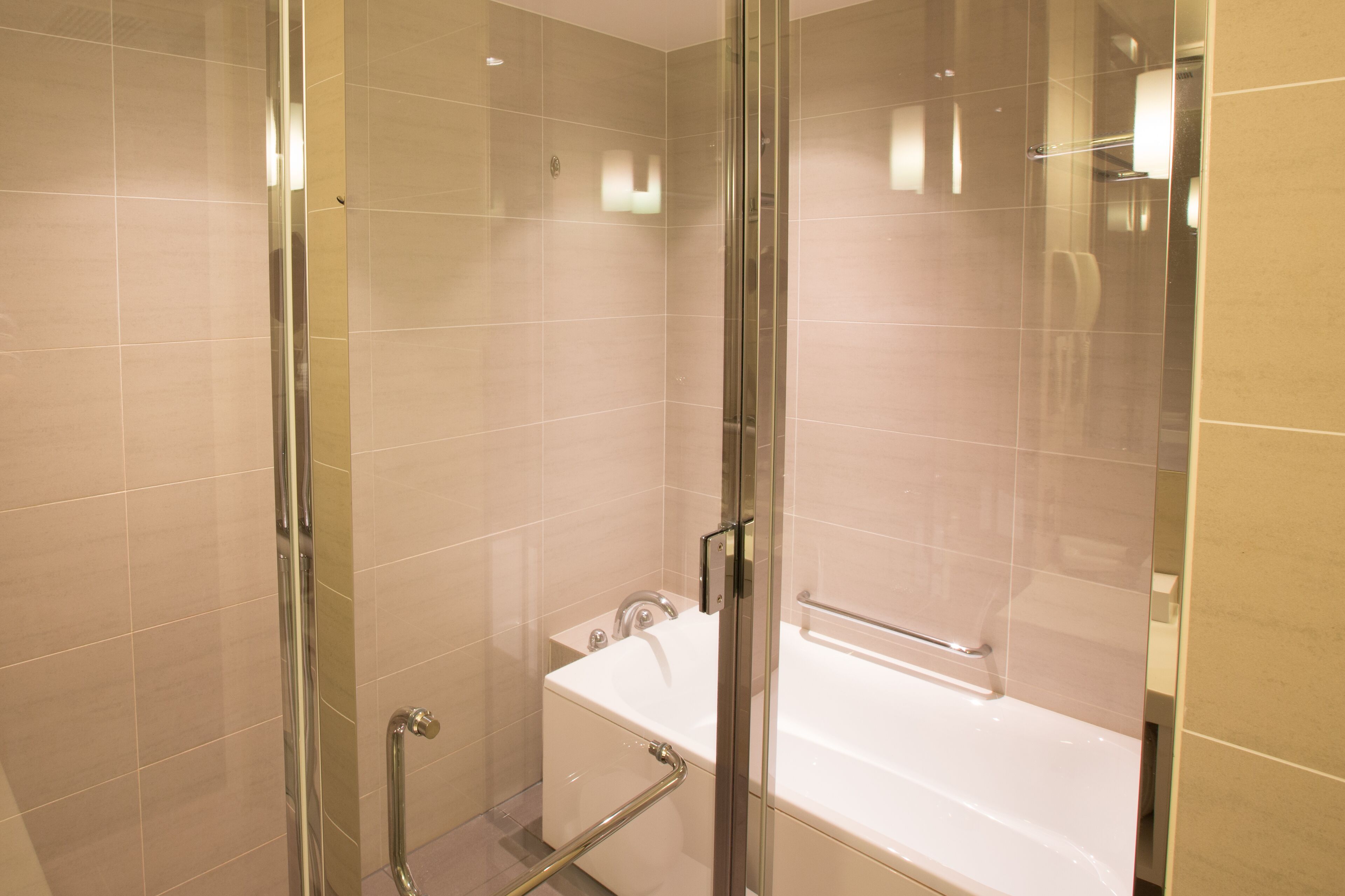 A modern bathroom with a glass-enclosed shower, a white bathtub, and a glass door.
