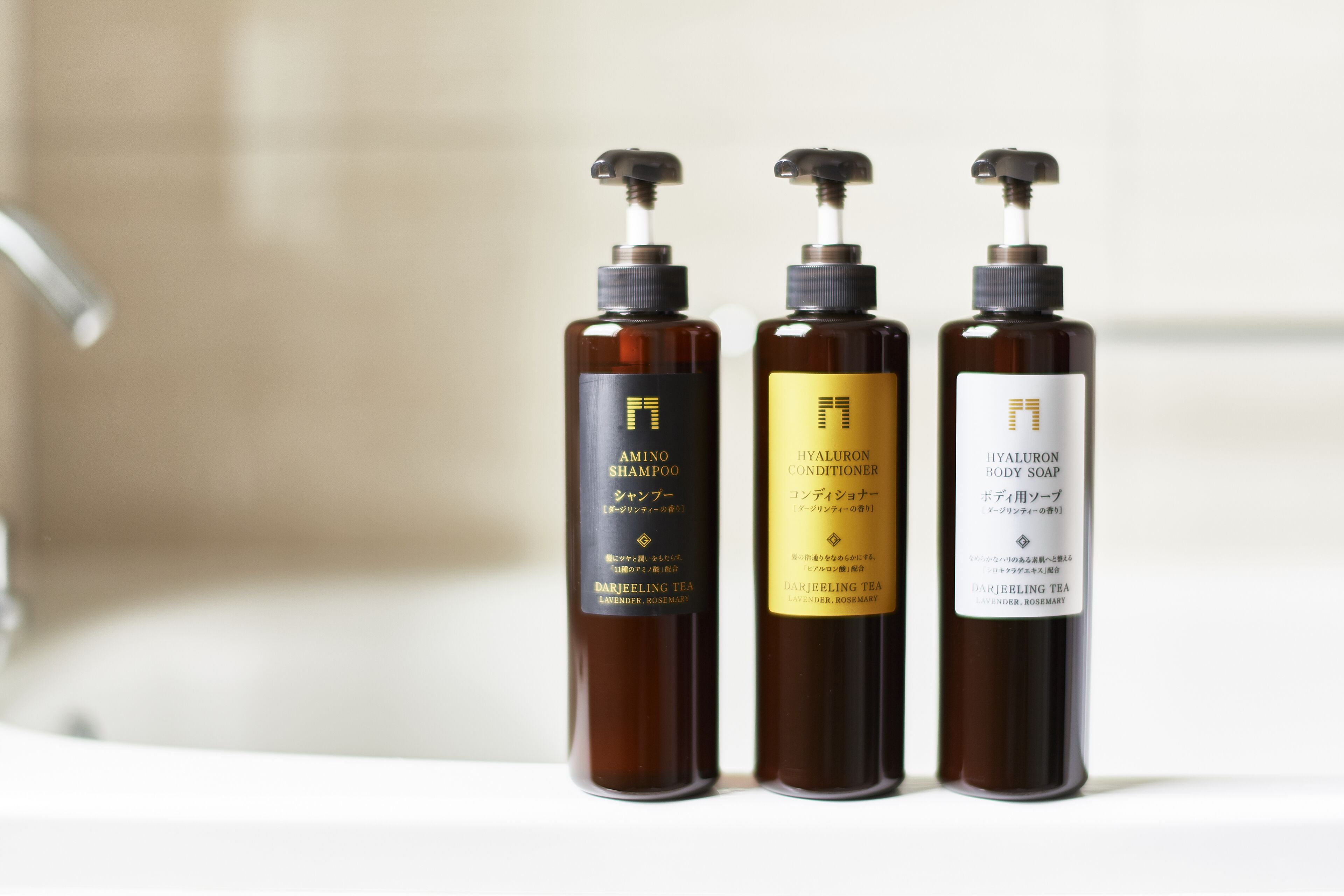 Tres botellas de productos para el cuidado corporal sobre una superficie blanca.