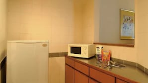 A compact kitchen with a refrigerator, microwave, and wooden cabinets. - Alpha Genesis Hotel Kuala Lumpur (Kuala Lumpur)