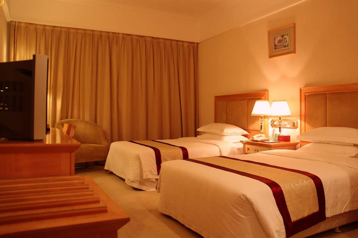 Une chambre d’hôtel avec deux lits, un bureau, une chaise et un téléviseur.