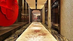A corridor with a patterned carpet, a red sculpture, and a glass elevator. - Veegle Hotel Hangzhou (Hangzhou)