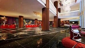 A spacious lobby with a marble floor, red seating, and a reception desk. - Veegle Hotel Hangzhou (Hangzhou)