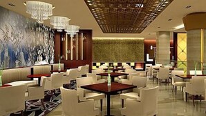 A modern restaurant with white chairs and tables, a chandelier, and a patterned wall. - Veegle Hotel Hangzhou (Hangzhou)