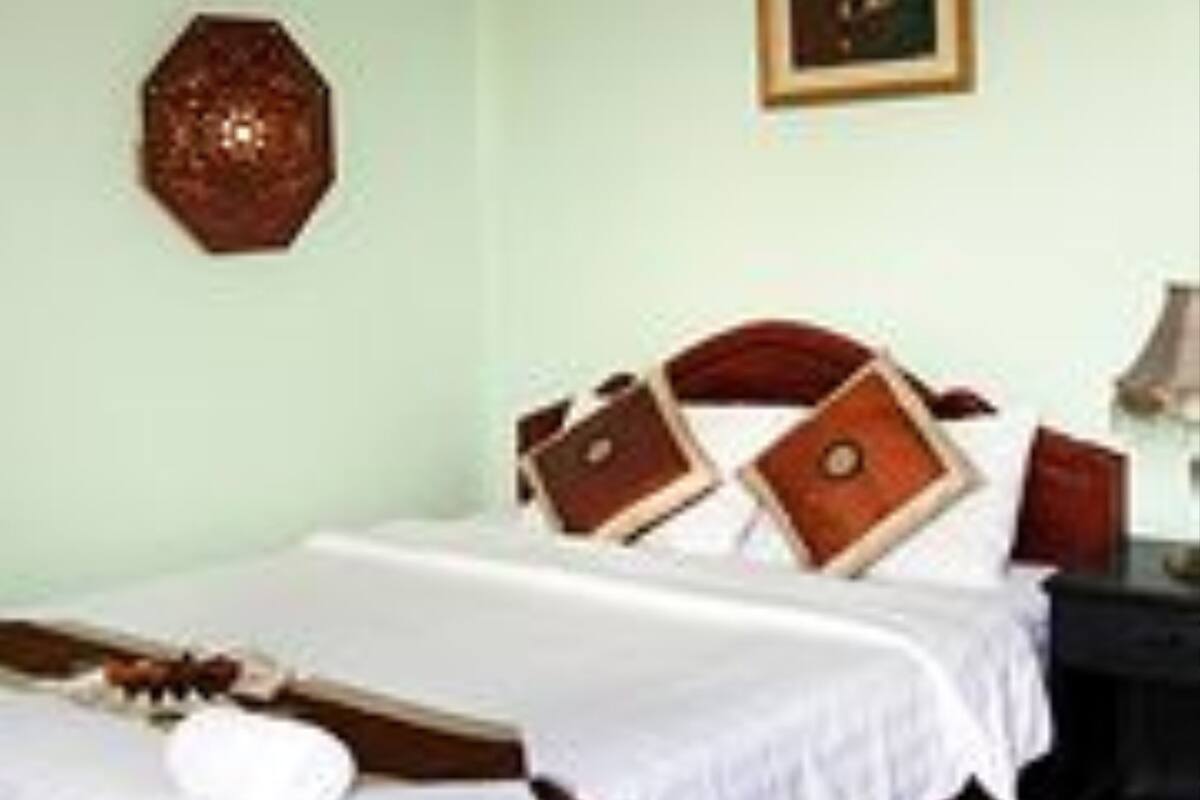 A hotel room with a bed, a nightstand, a lamp, and a painting on the wall.