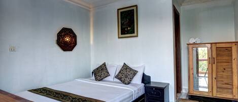 A bedroom with a bed, a nightstand, a wooden cabinet, and a wall-mounted decorative piece.
