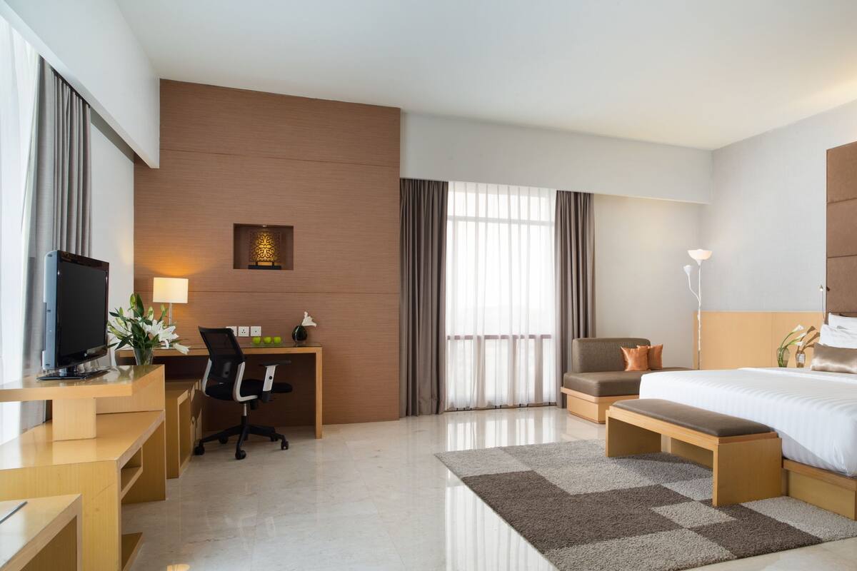 A hotel room with a bed, desk, chair, and a TV.