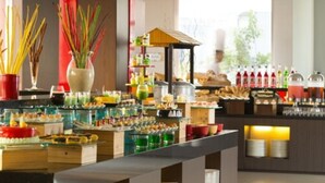 Un área de bufé con diversas opciones de comida y bebidas, una estación de cocina en vivo y vistas al exterior.