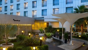 Un patio de hotel con piscina, mobiliario exterior y fachada de edificio moderno.
