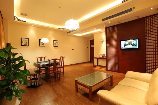 A modern living room with a wooden coffee table, a sofa, and a dining area with chairs and a table. - Cedar Hotel (Guangzhou)
