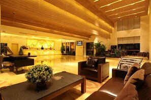 A spacious lobby with a wooden ceiling, a reception desk, seating area, and a television screen. - Cedar Hotel (Guangzhou)