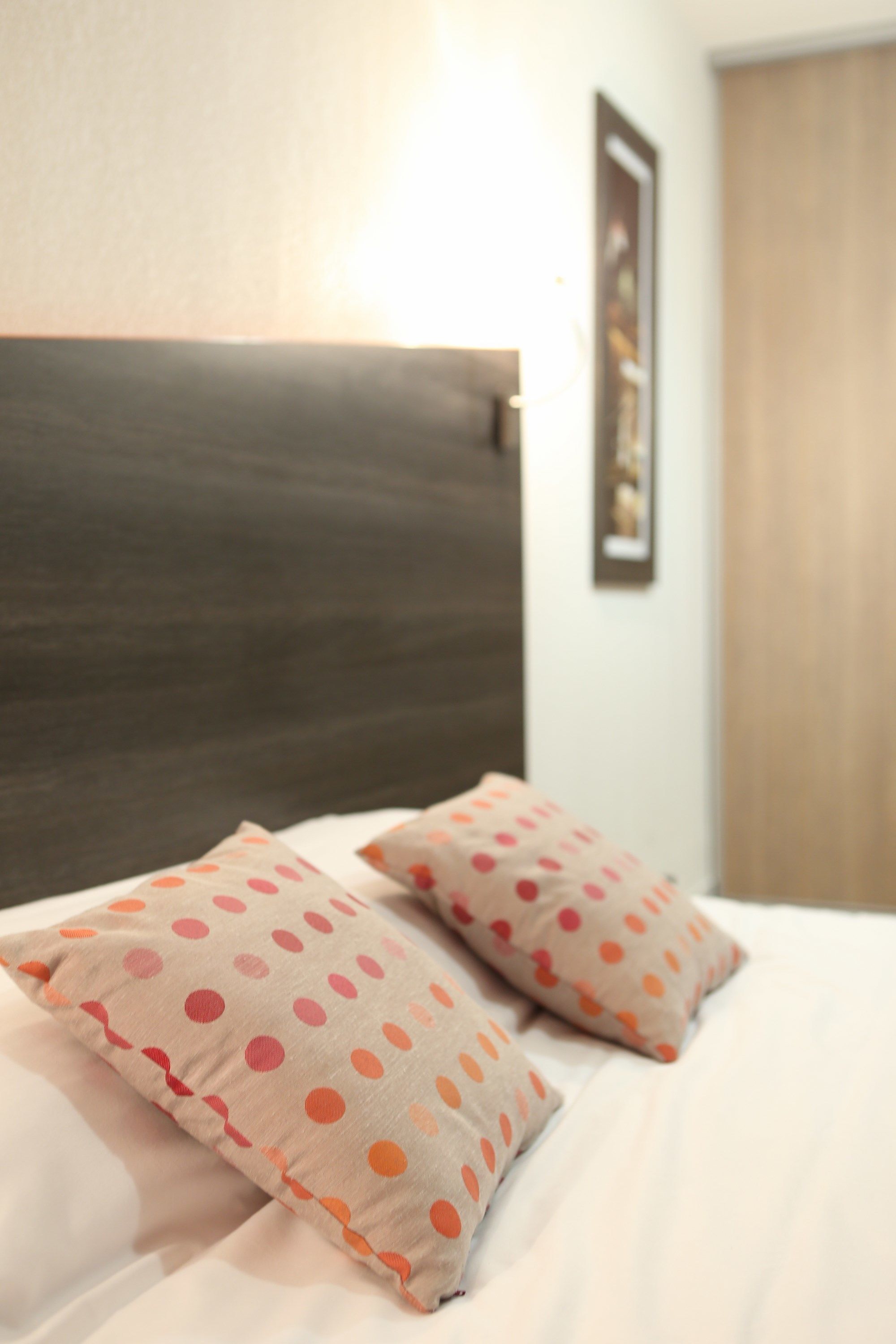 Una cama con cabecera oscura y dos almohadas estampadas con lunares.