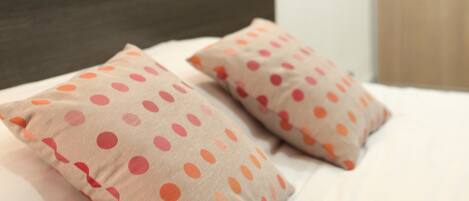 Una cama con cabecera oscura y dos almohadas estampadas con lunares.
