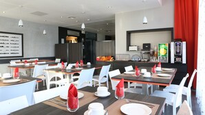 Un espace de restauration moderne avec des tables dressées, des chaises blanches et des serviettes rouges.
