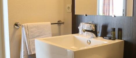 A bathroom with a white sink, a mirror above it, and an orange cabinet below.