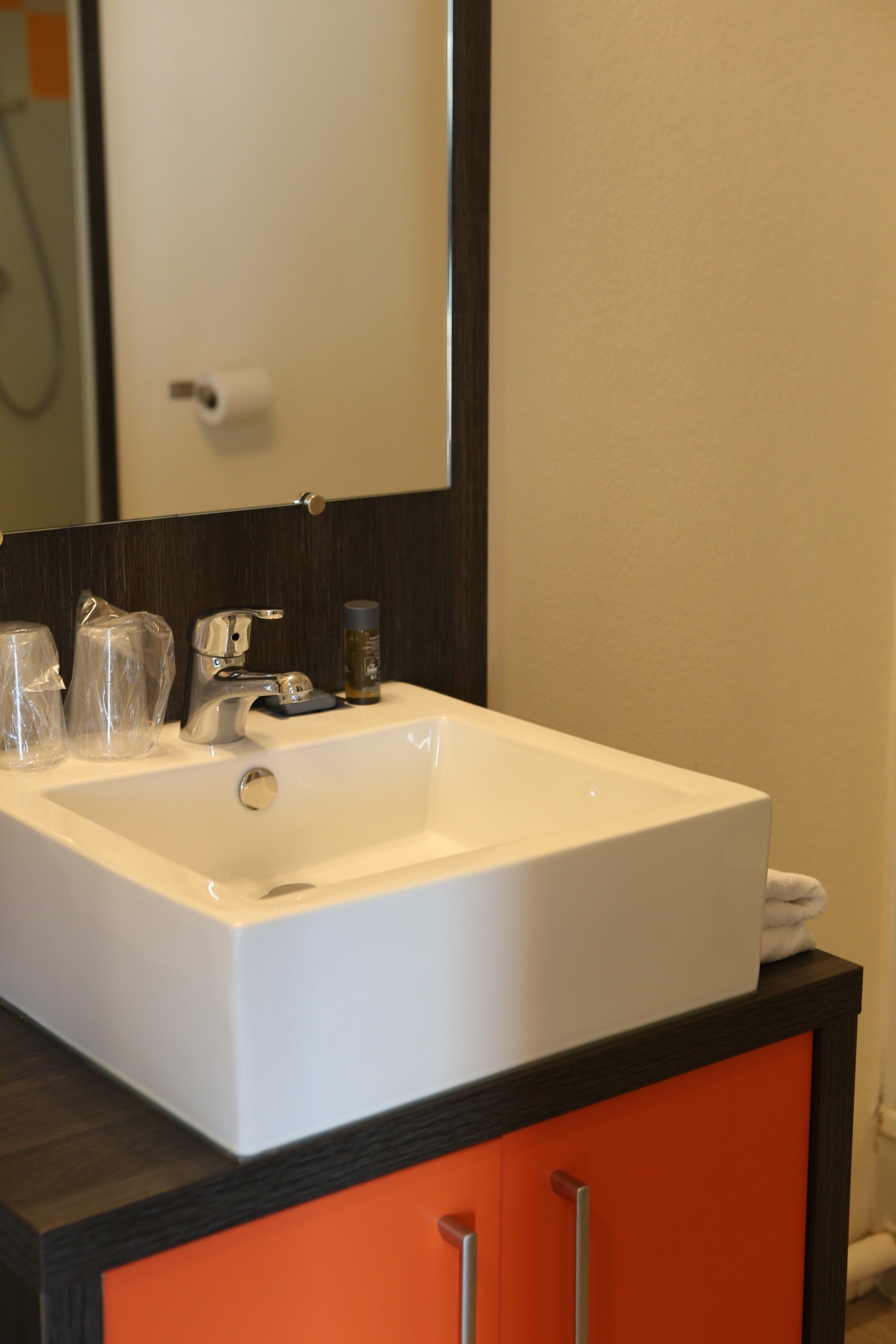 Un lavabo con espejo, toallero y dispensador de jabón.