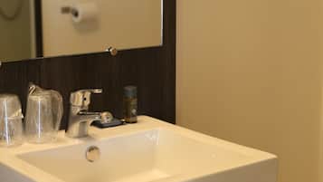 Un lavabo con espejo, toallero y dispensador de jabón.