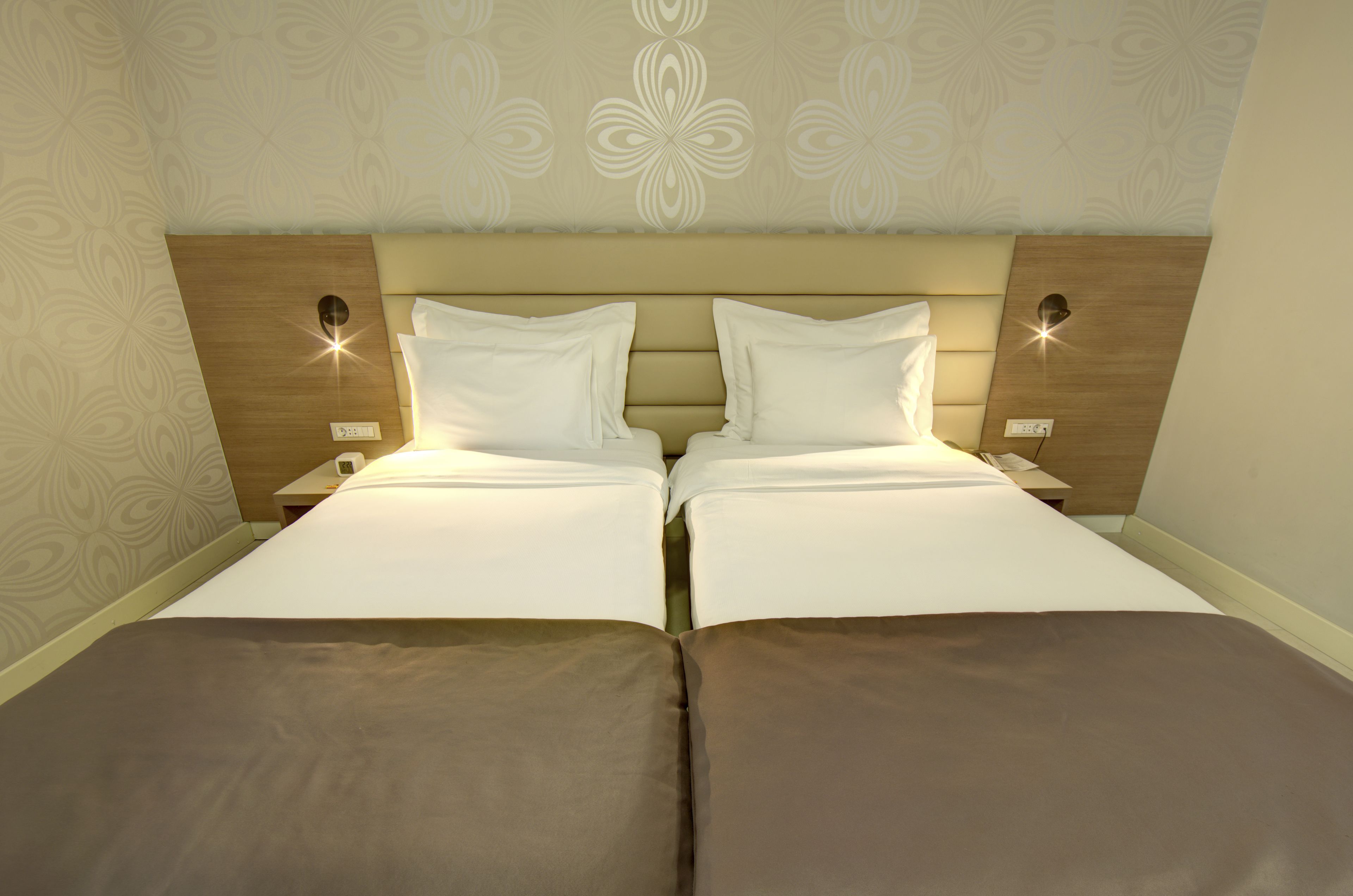 A double bed with a headboard, two bedside tables, and wall sconces.