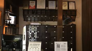 A reception desk with a coat of arms above, a computer, and a sign about coronavirus prevention.