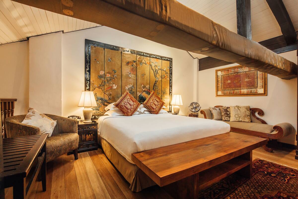 A traditional room with a large bed, wooden furniture, and a decorative tapestry.