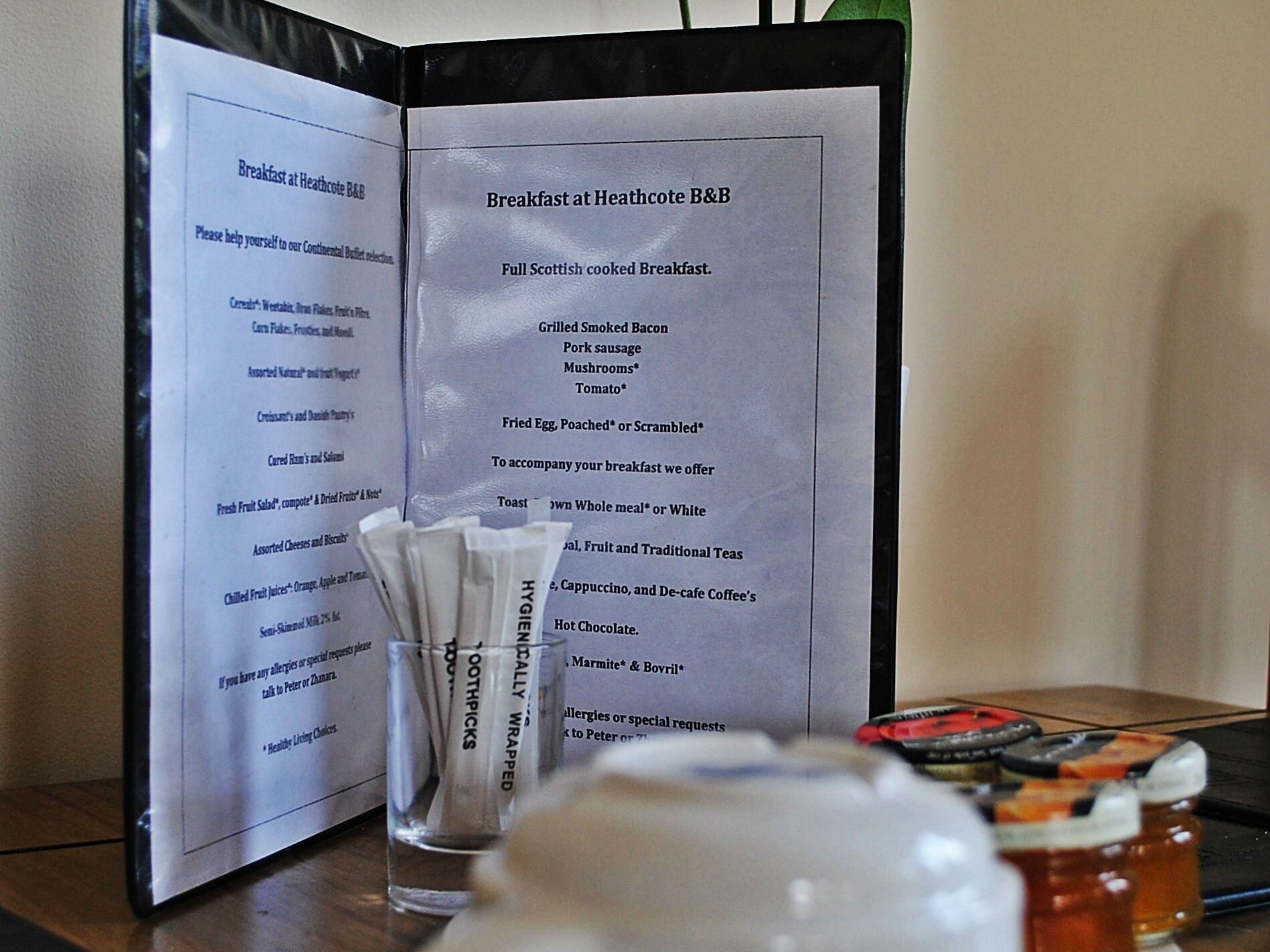 A menu for breakfast at Heathcote B&B listing items like grilled bacon, pork sausage, mushrooms, tomato, fried egg, toast, whole meal, white bread, fruit, traditional teas, cappuccino, de-cafe coffee, hot chocolate, marmite, and Bovril.