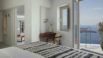 A modern bedroom with a large bed, a desk, and a chair. There is a view of the sea through a balcony.