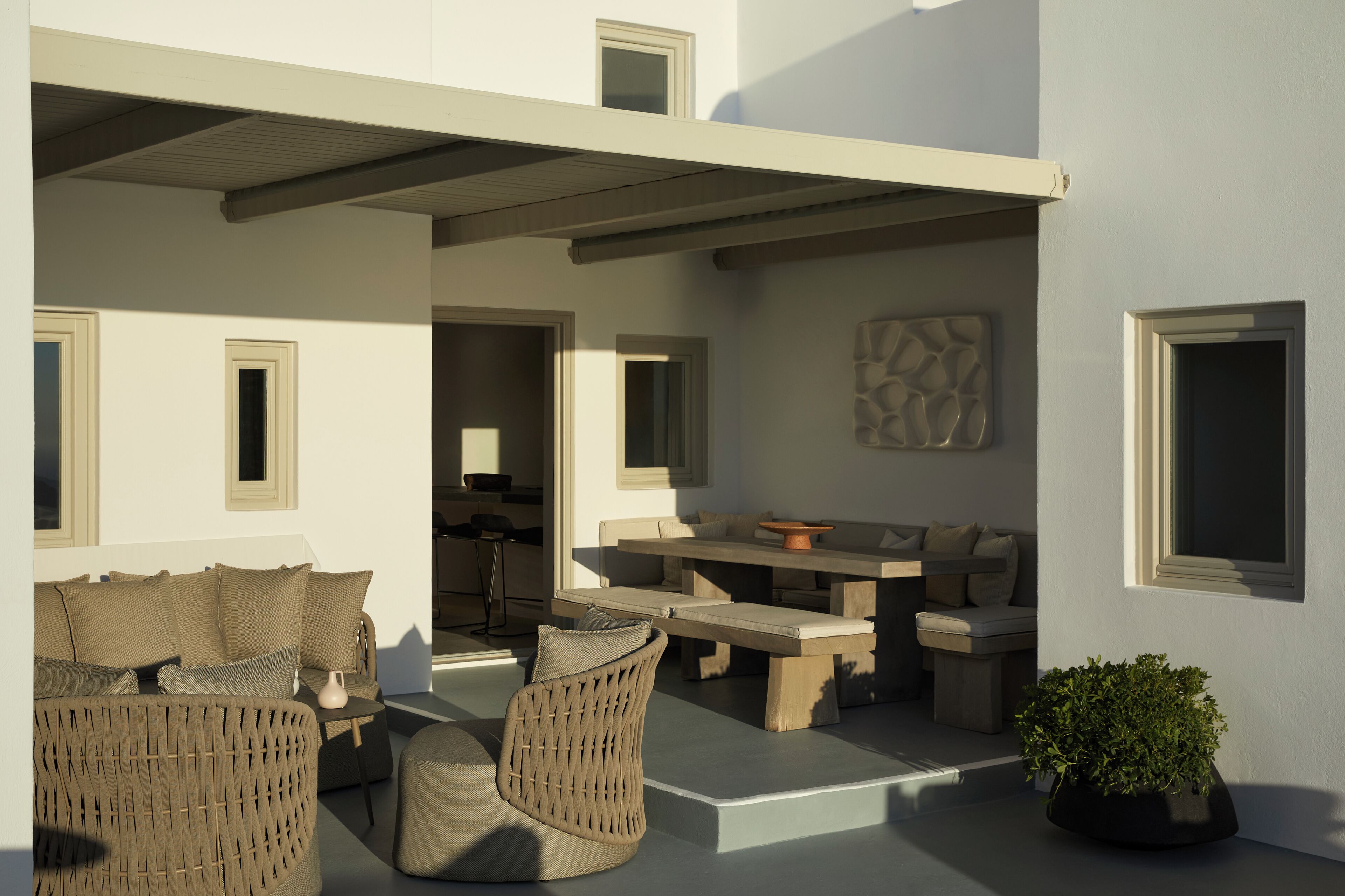 A modern outdoor seating area with wicker furniture, a stone table, and a potted plant.