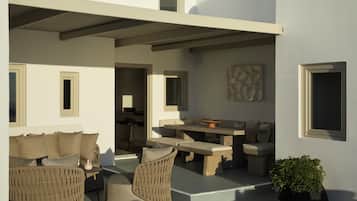 A modern outdoor seating area with wicker furniture, a stone table, and a potted plant.