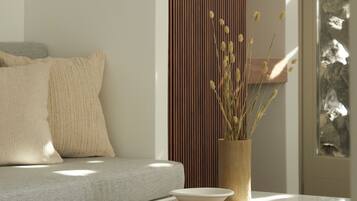 A modern living room with a sofa, a wooden sideboard, a marble coffee table, and a vase with dried plants.