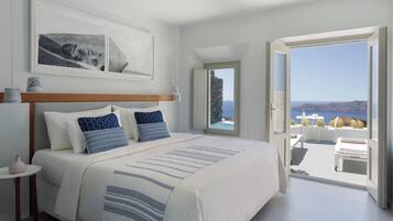 A bedroom with a large bed, a view of the sea, and a balcony with outdoor furniture.