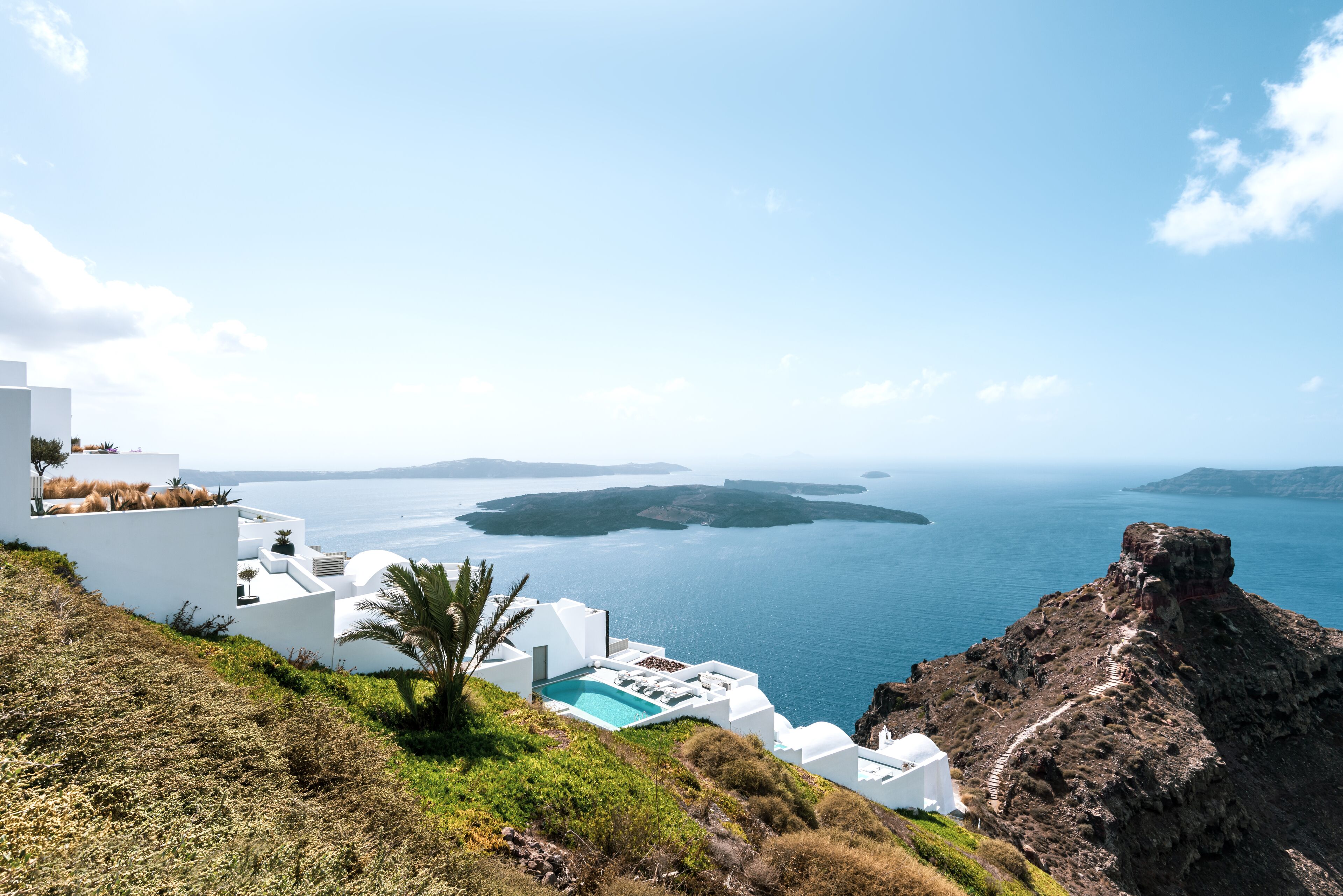 A white building with a pool and a view of the sea.
