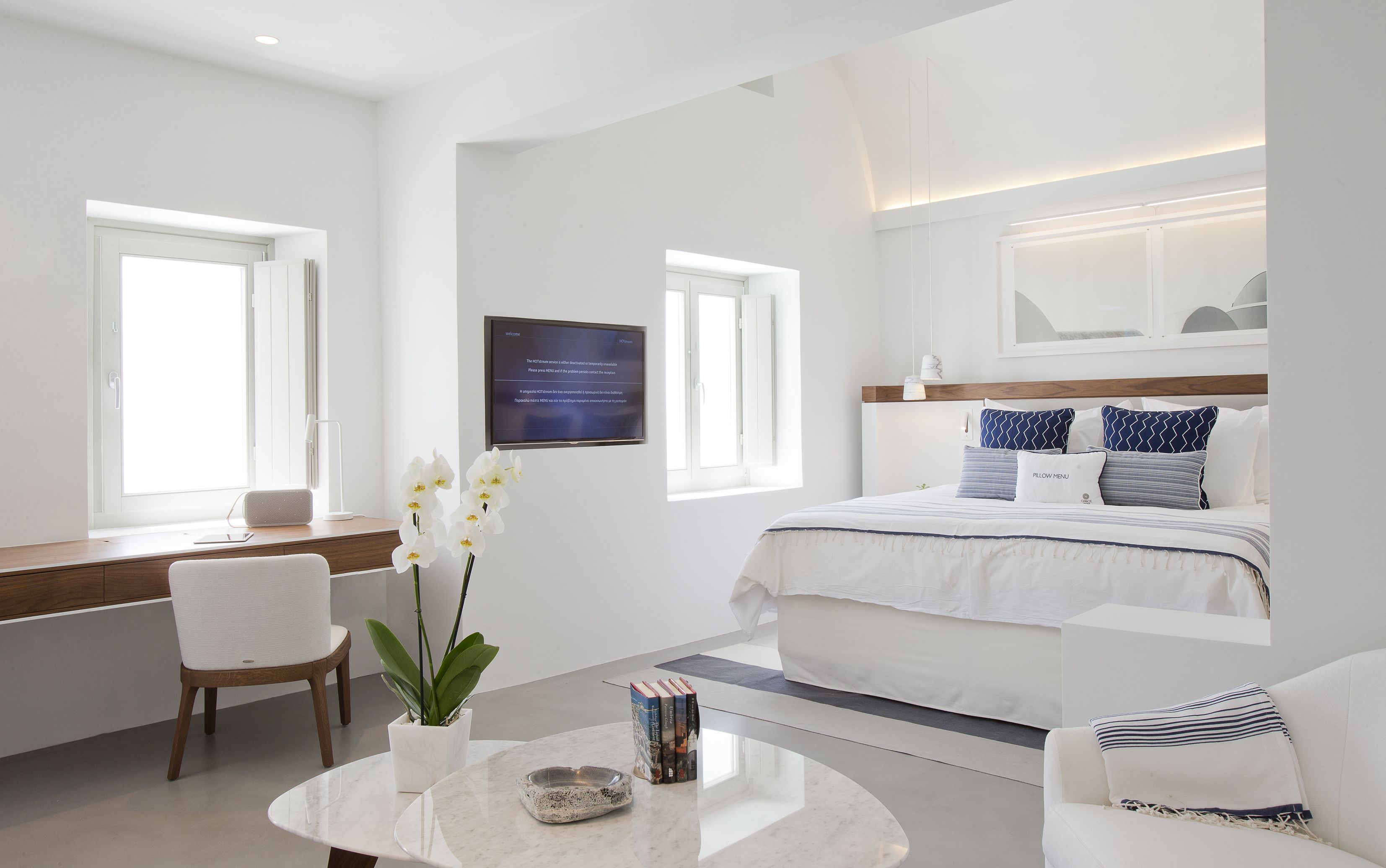 Habitación de hotel moderna con una cama, un escritorio, una silla, un televisor y una ventana.