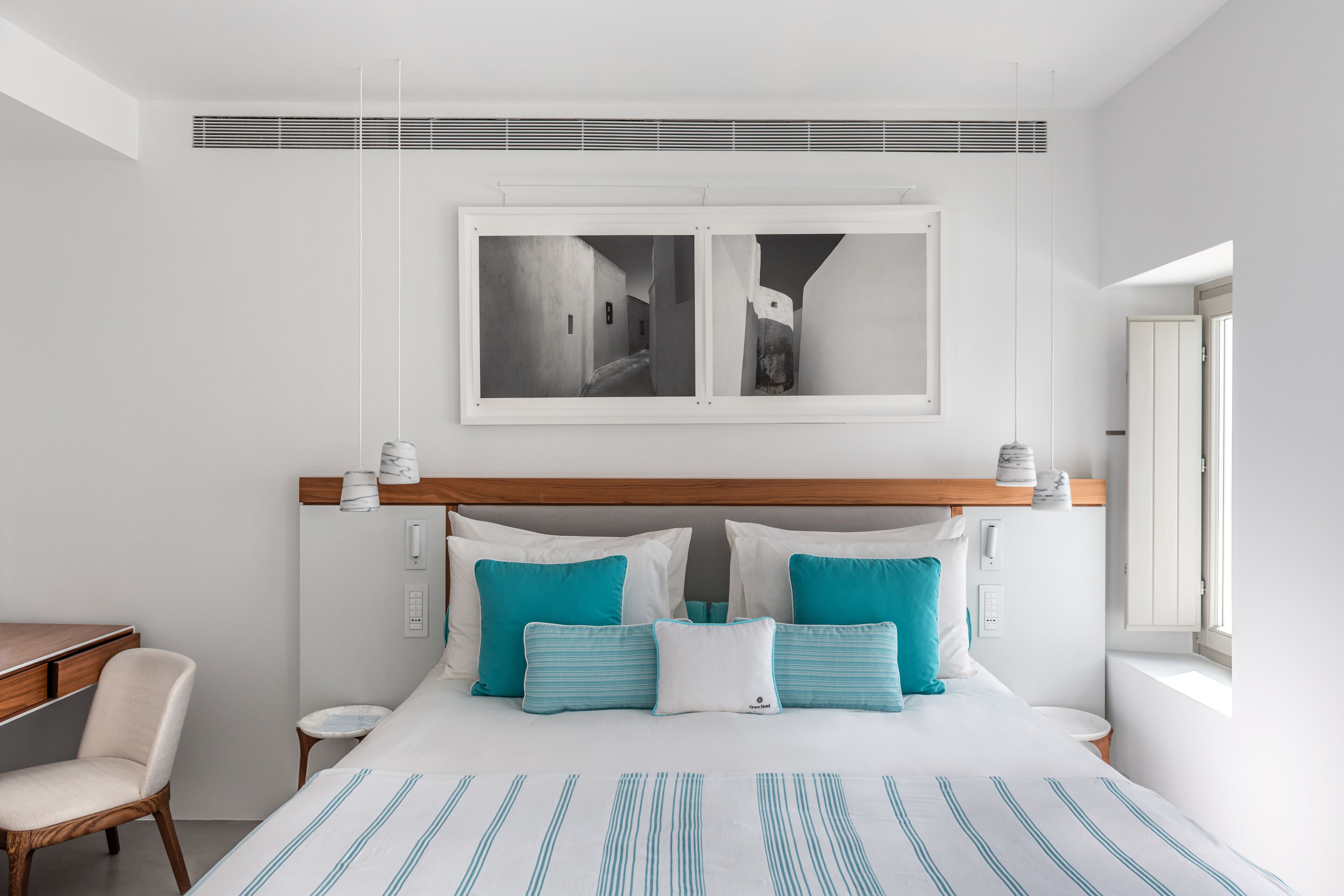 Una camera d'albergo moderna con un letto grande, una testiera in legno, una scrivania e una sedia.
