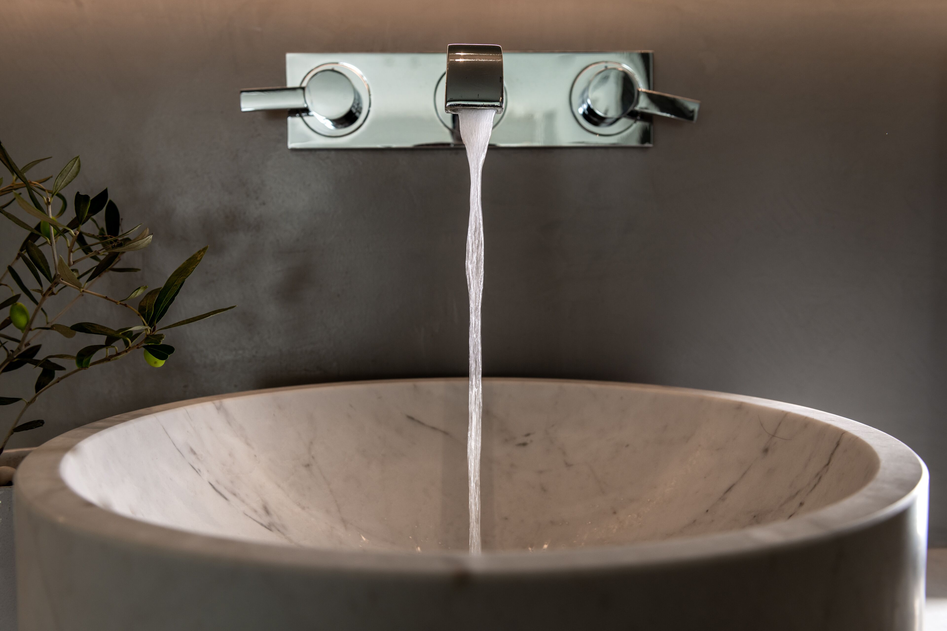 A marble sink with water flowing from a modern faucet.