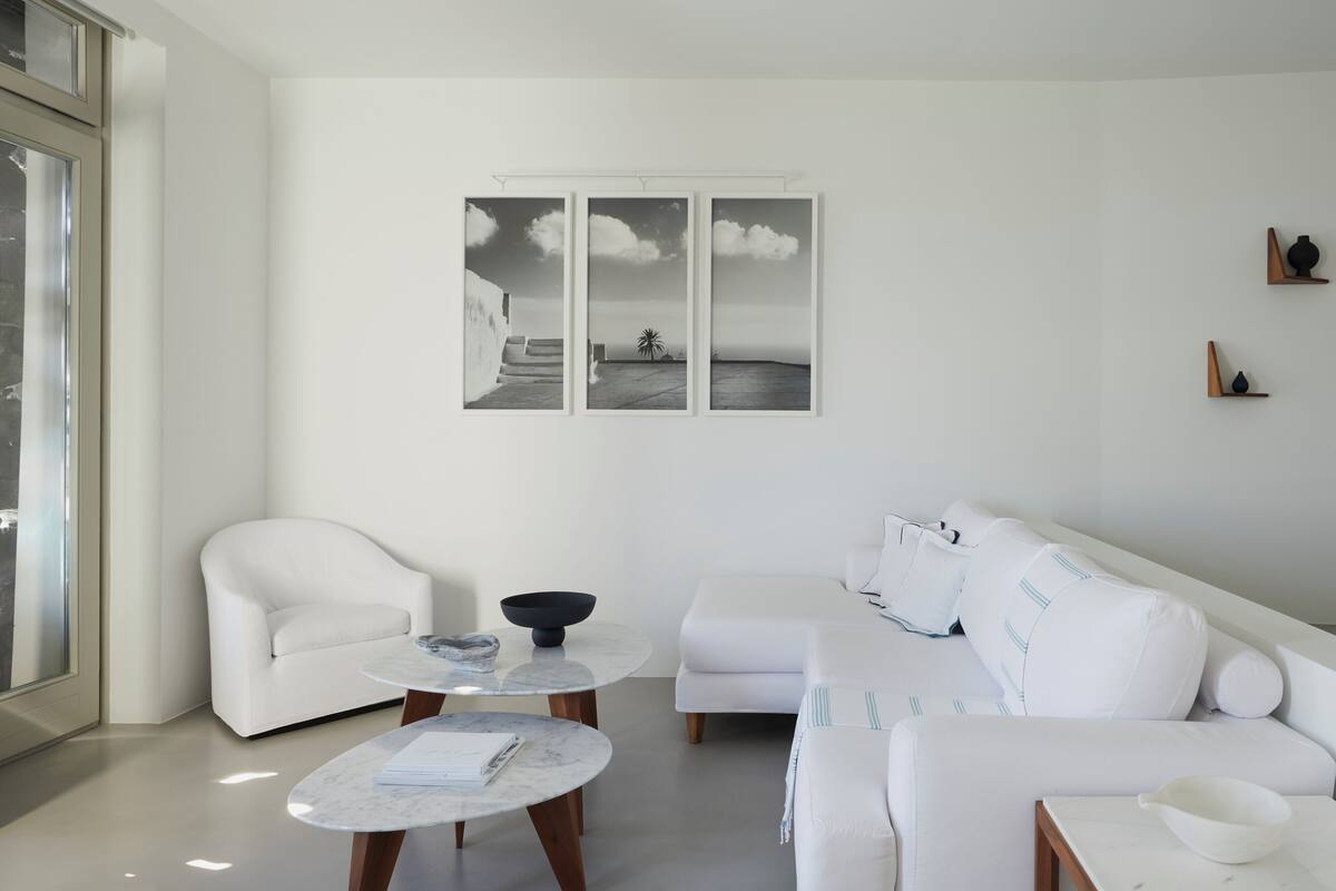 A modern living room with a white sofa, two round tables, and a wall-mounted artwork.