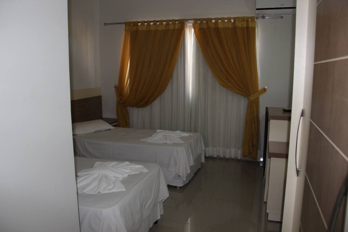 Habitación de hotel con dos camas, un escritorio pequeño y zona de ducha.