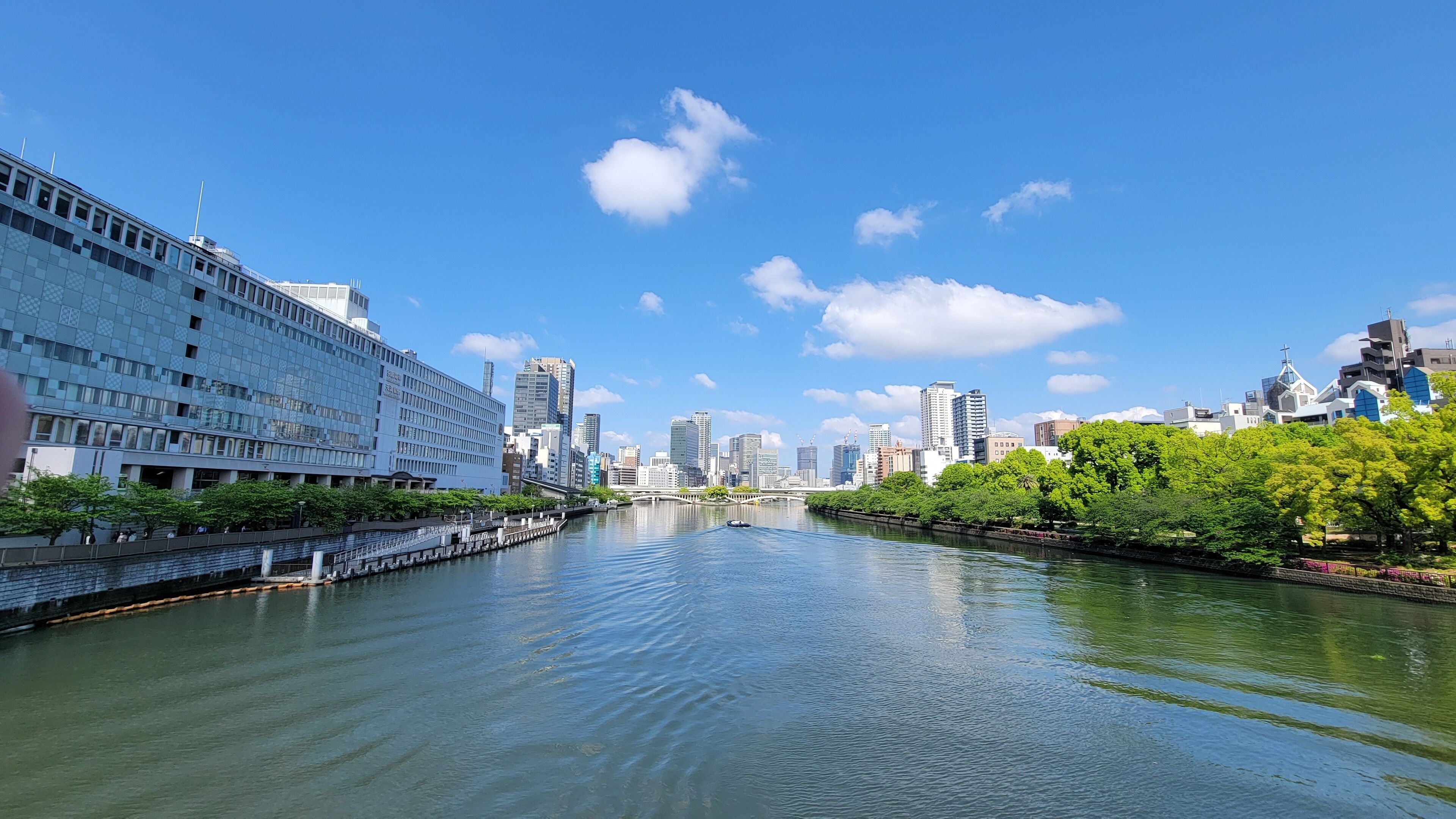 A river with a bridge, modern buildings, and a clear sky.