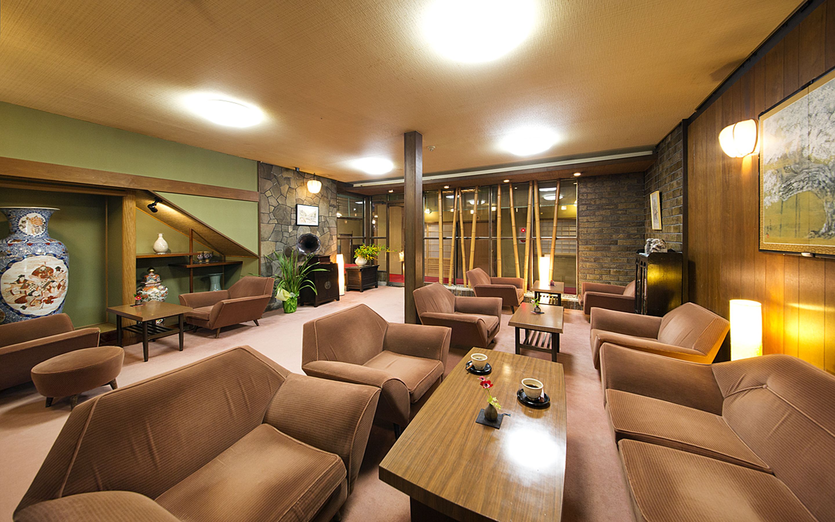 Un área de lounge moderna con sofás, mesas y un gran jarrón decorativo.