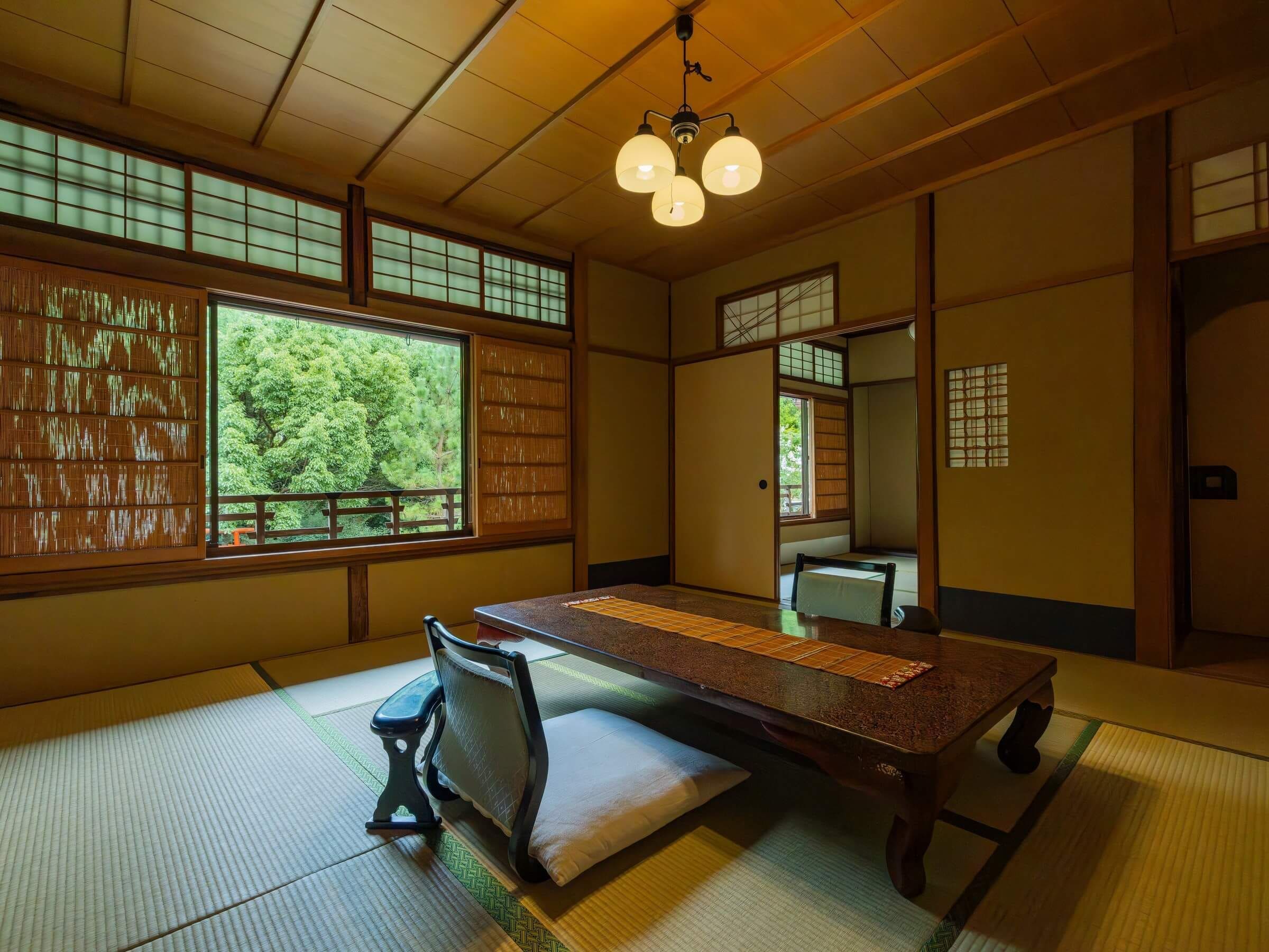 A traditional Japanese room with tatami flooring, a low table, a bench, and sliding doors.