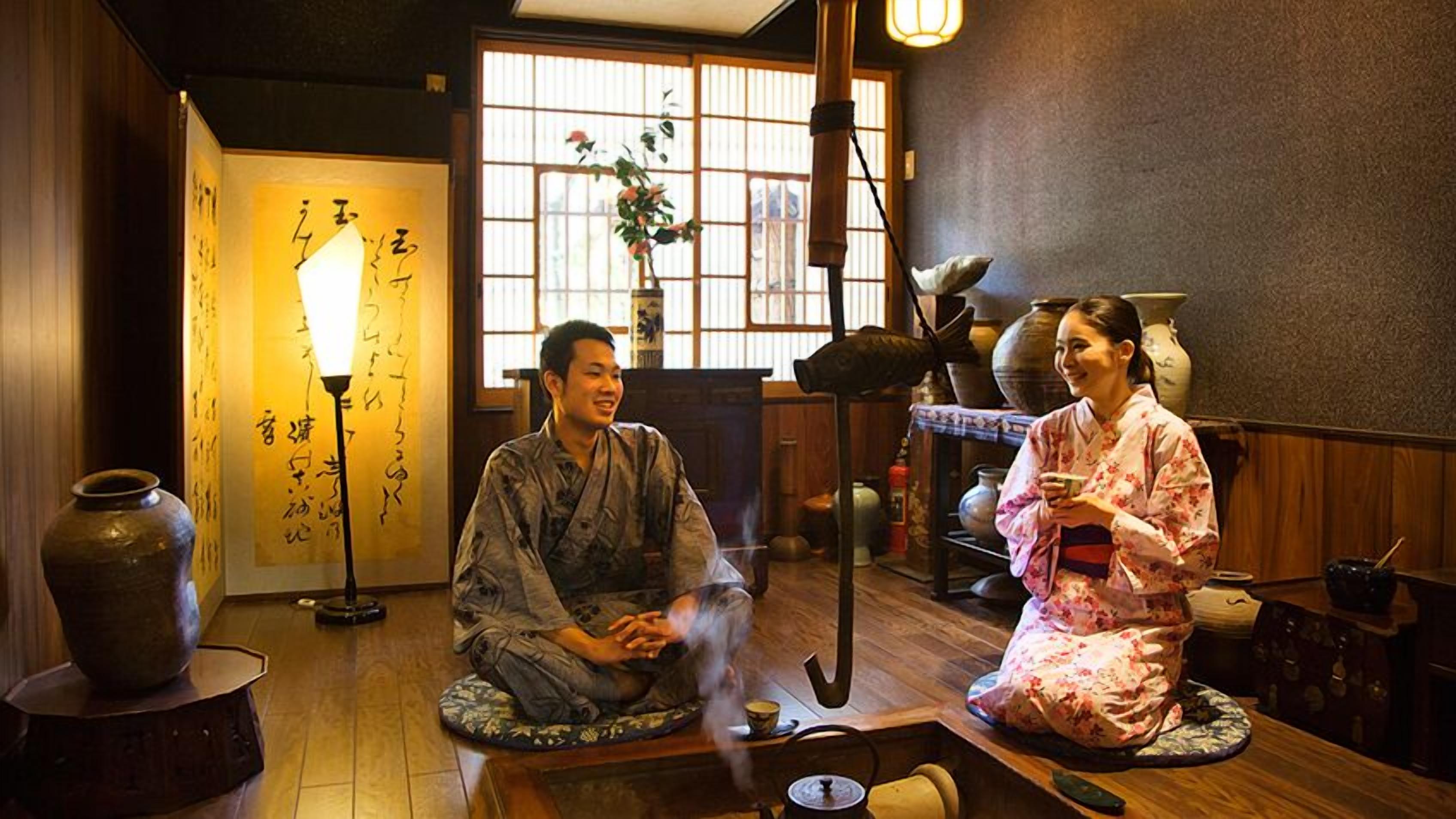 A traditional Japanese room with tatami flooring, a tea ceremony setup, and calligraphy on the wall.