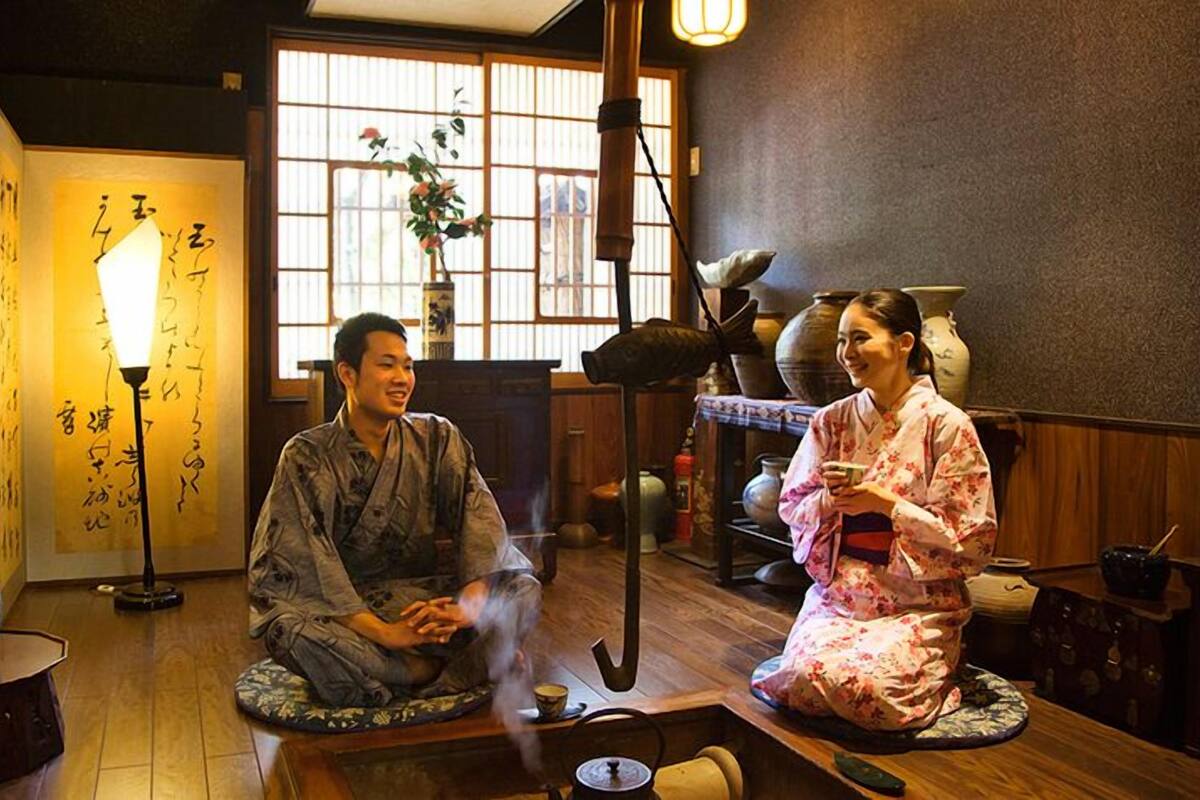 A traditional Japanese room with tatami flooring, a tea ceremony setup, and calligraphy on the wall.
