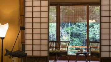 A traditional Japanese interior with tatami mats, a tea set, and sliding doors leading to a garden.