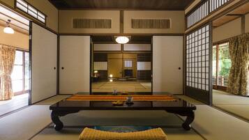 Una habitación japonesa tradicional con suelo de tatami, una mesa baja y puertas correderas.