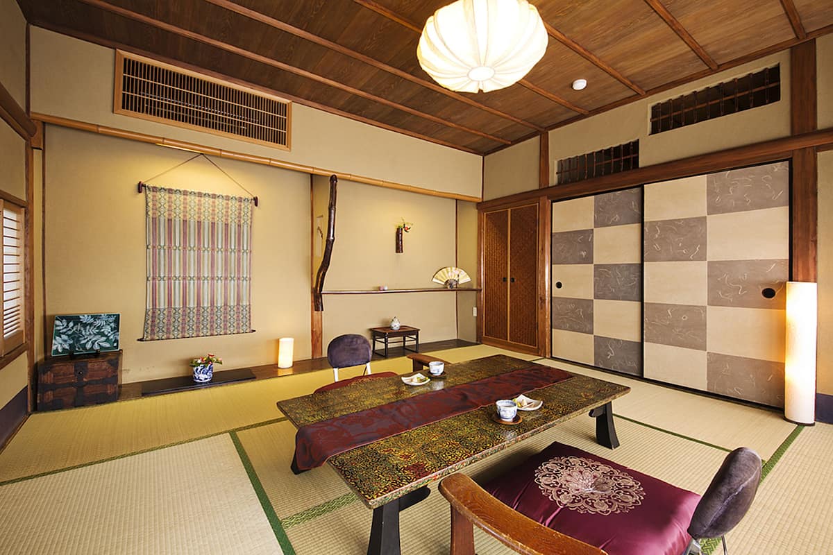 A traditional Japanese room with tatami flooring, a low table, and a sliding door.