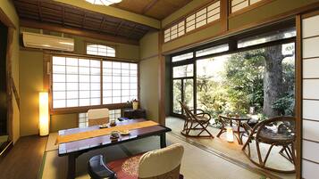 A traditional Japanese room with tatami flooring, a low table, and sliding doors leading to a garden.