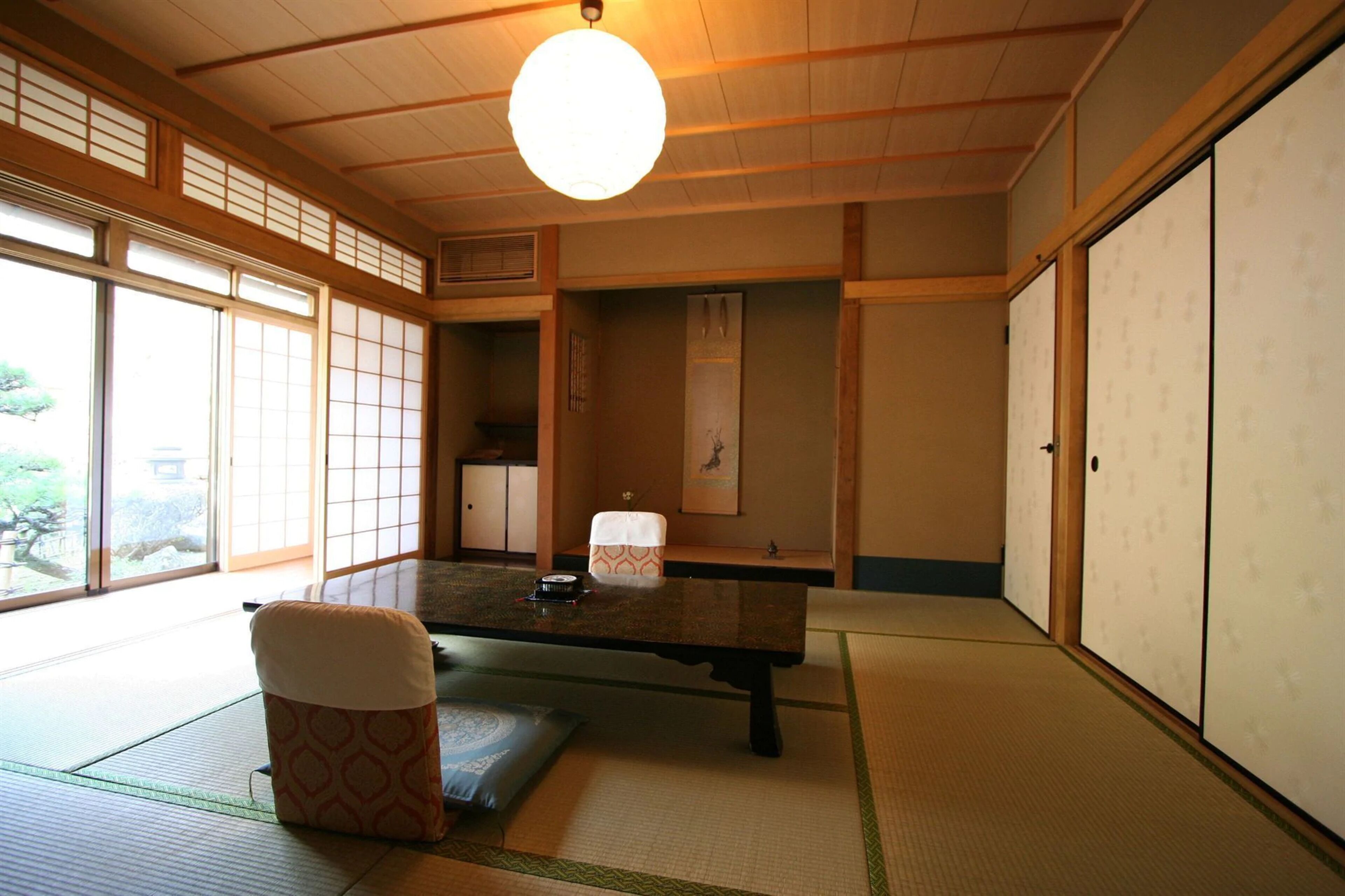 Una habitación japonesa tradicional con suelo de tatami, una mesa baja y puertas correderas.