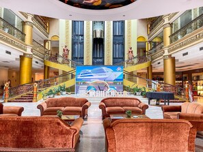 A grand lobby with a central stage, multiple staircases, and luxurious seating areas. - Pacific Palace Hotel (Batam)