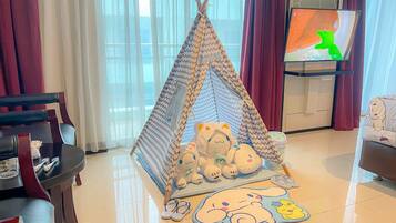 Una sala de estar acogedora con una tienda tipi para jugar, juguetes suaves y un televisor sobre un mueble bajo.