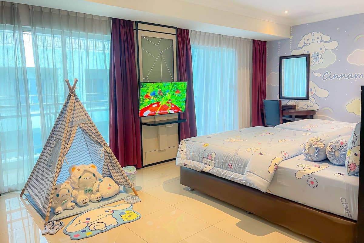 A bedroom with a bed, a TV, a tent-like play area, and a wall with a cartoon character.