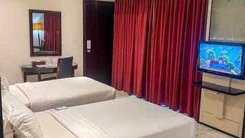 Una habitación de hotel con dos camas, un escritorio, un televisor y un espejo.